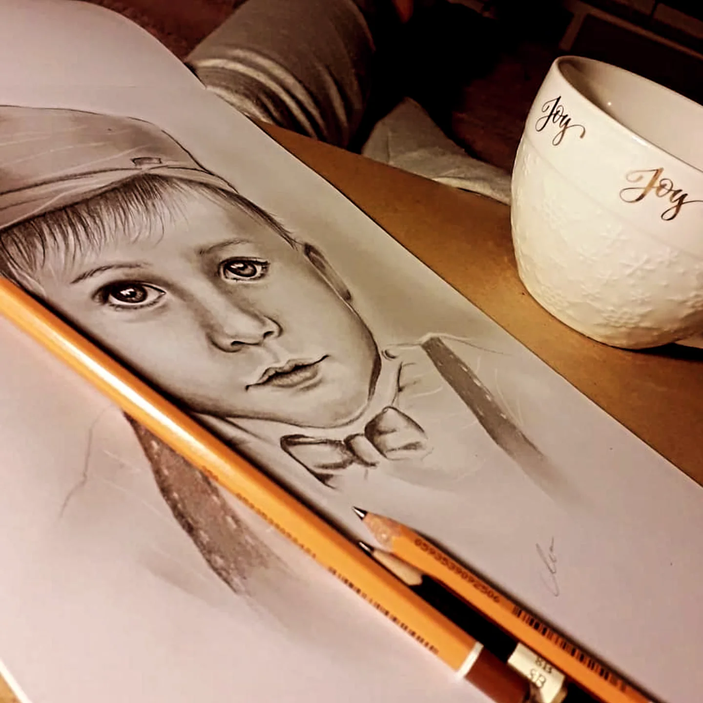 Ołówkowy portret chłopca w czapce i muszce